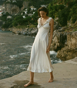 In a soft, lightweight stretch silk satin, the Arleen Dress features delicate cap sleeves and embroidered ruffles adorning the plunging back, V-neckline, and hem. A fitted bodice with an invisible side zipper gives way to an ankle-grazing bias-cut skirt while a baby snap fastens at the back of the neck.