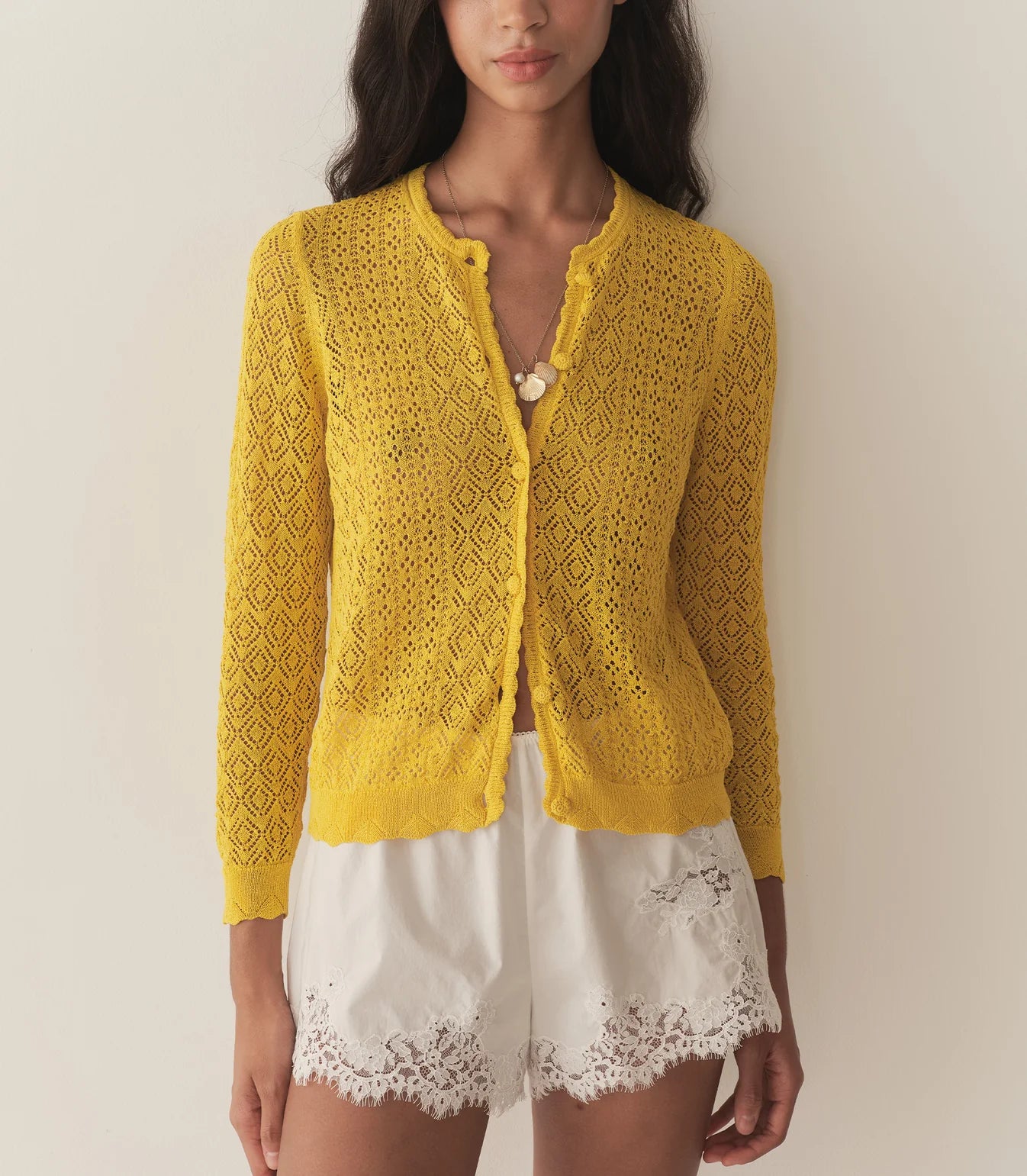 The Diane Cardigan by Doen is a wardrobe essential that effortlessly elevates any outfit with understated sophistication. Its intricate pointelle design draws inspiration from Victorian bobbin lace, creating visual interest while maintaining an airy, breathable feel. Crafted from a luxurious viscose blend, this cardigan drapes gracefully without excess weight, making it perfect for layering across seasons. 