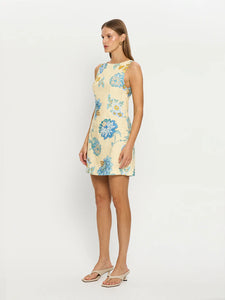 The Giselle Mini Dress combines intricate blue-toned vine florals with a fresh butter base, creating a refined and elegant look. Made from 100% linen, it offers breathable comfort and a lightweight feel ideal for warm weather. The dress features a sophisticated high boat neck and a square back neckline accented with contrast ties, adding a delicate, tailored finish to the silhouette. Perfect for those seeking both style and comfort, this piece seamlessly blends artistry with effortless wearability.