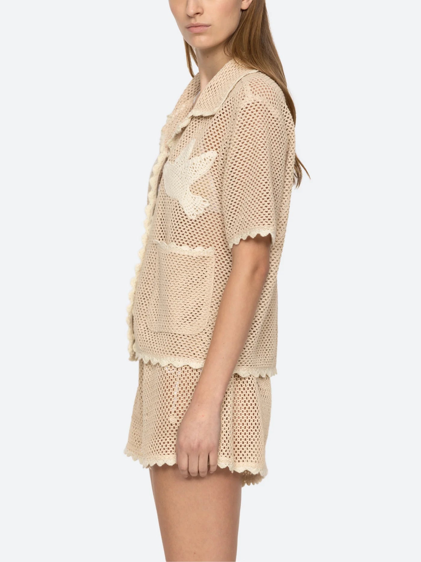 Upgrade your wardrobe with the Sally Crochet Shirt by SEA NY! This mid-weight, open knit shirt is designed for a slightly loose fit and is appliquéd with two delicate birds. Traced with scalloped trims, this beige and white crocheted cotton shirt is both stylish and comfortable. Button fastenings add a polished touch, making it perfect for any occasion.