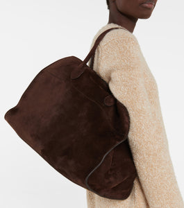 Discover the ultimate in luxurious and everyday style with The Row's Soft Margaux 17 suede tote. Expertly crafted in Italy from supple mocha brown suede, this bag features two rolled top handles, gusseted sides, and a spacious canvas lining. Upgrade your wardrobe with this effortlessly chic and versatile bag.