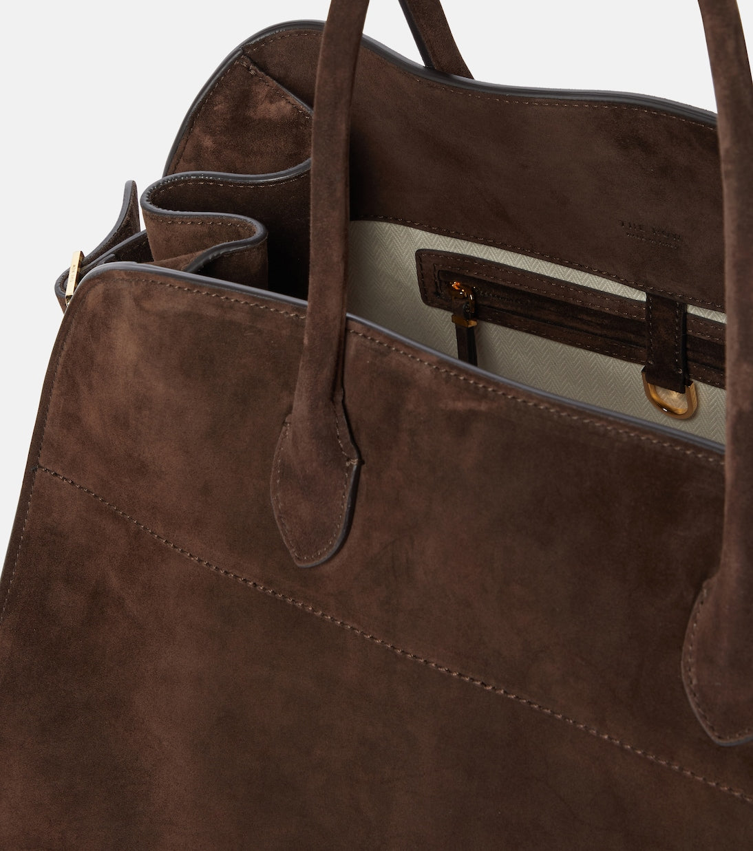 Discover the ultimate in luxurious and everyday style with The Row's Soft Margaux 17 suede tote. Expertly crafted in Italy from supple mocha brown suede, this bag features two rolled top handles, gusseted sides, and a spacious canvas lining. Upgrade your wardrobe with this effortlessly chic and versatile bag.