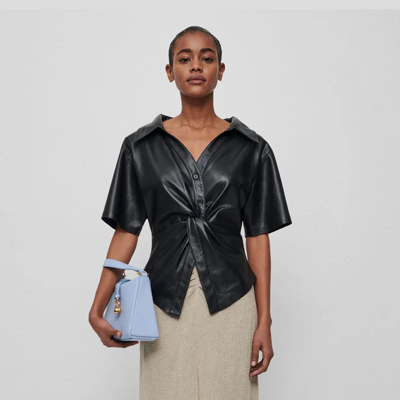 Introducing the Top Thora - a sleek women's short sleeve shirt made with vegan leather and a twisted v-neck design. Perfect for those looking for a versatile and stylish option for the spring and summer season. With its vegan leather material, this blouse offers a touch of temperament and simplicity.