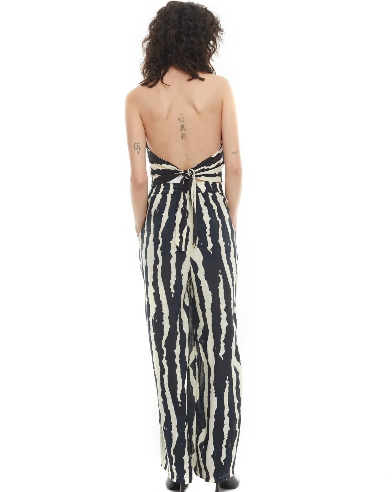 Elevate your style with the Ensemble Leigh set! Show off your back with the sexy backless halter neck top. The elastic waist and wide leg pants offer comfort and versatility, making it perfect for any occasion. Embrace your wild side with the zebra print design.