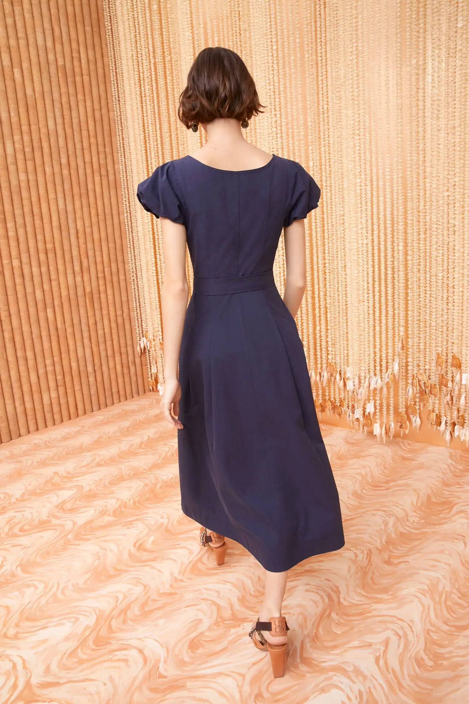 A classic Ulla Johnson silhouette perfect for daytime, the Rhea Dress is cut from our sleek cotton chino in midnight blue and is neatly tailored with corset-inspired seams. The puff sleeves feature softly rolled edges, while the removable belt at the fitted bodice adds definition. This midi-length style has side pockets and fastens with tonal buttons through the front.