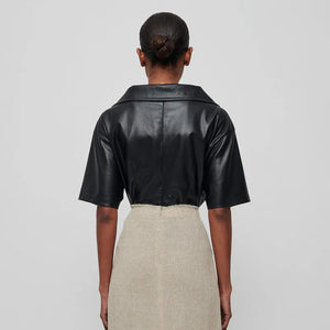 Introducing the Top Thora - a sleek women's short sleeve shirt made with vegan leather and a twisted v-neck design. Perfect for those looking for a versatile and stylish option for the spring and summer season. With its vegan leather material, this blouse offers a touch of temperament and simplicity.