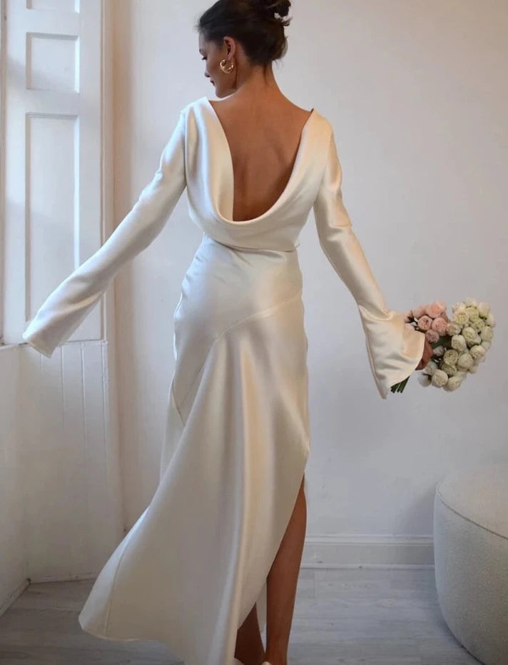 This ankle length wedding dress features a soft fluted sleeve which falls delicately at the wrist. Inspired by the 20s film star Billie Dove, this chic bridal gown is crafted using luminous silk satin in an antique soft gold. This is an incredibly luxurious piece with a beautiful fluid drape.