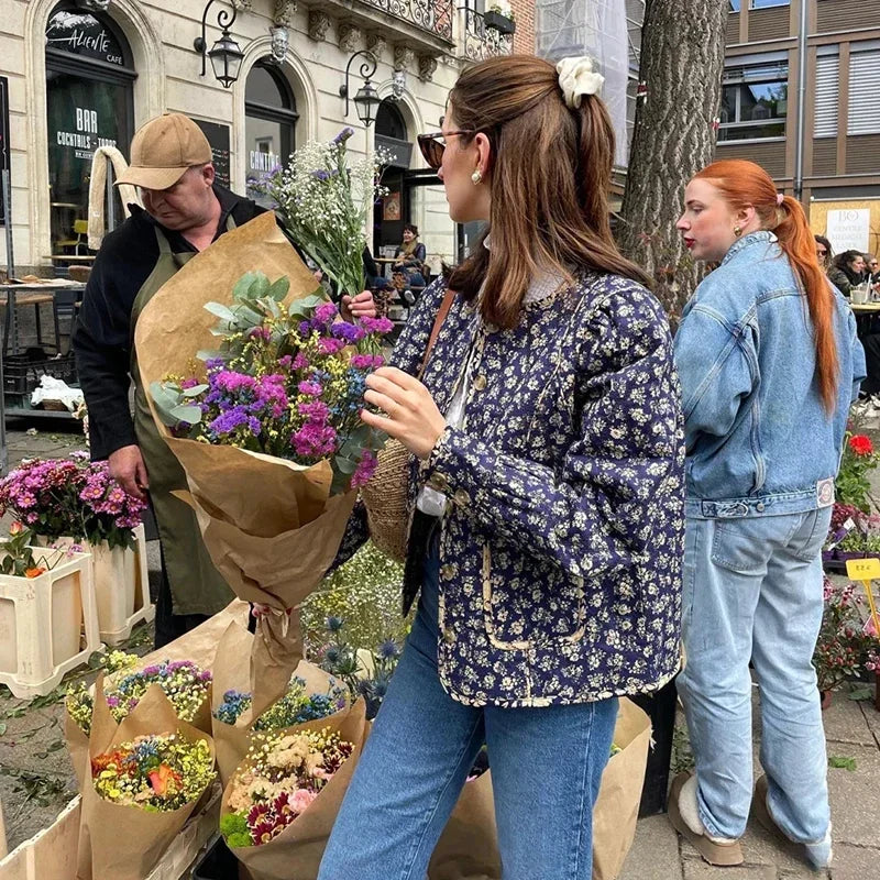 Stay stylish and warm with our Veste Brigitta jacket. Featuring a retro blue and white porcelain floral design and a round collar, this quilted jacket will elevate any outfit. The perfect combination of fashion and function, it's a must-have for any woman's wardrobe.