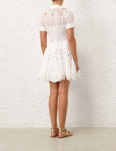 This cotton mini dress features short sleeves and a front center placket for a polished look. Its delicate scalloped hemline and intricate placement trim add refined detailing, while the included separate slip ensures comfortable coverage and smooth layering. Ideal for warm weather, this dress combines breathable fabric with elegant design elements.