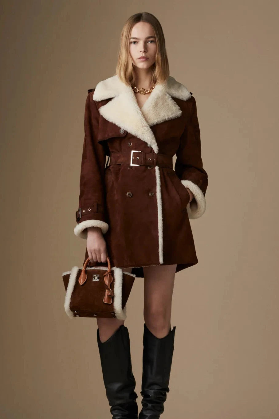 Take on the world in the bold and adventurous Suede Shearling Coat by Ermanno Scervino. Hand-dyed and crafted from luxurious suede, this double-breasted coat features military-inspired buttons and a striking trench coat design with shoulder loops and strap cuffs. Its light gold galvanic plating adds a touch of daring sophistication.