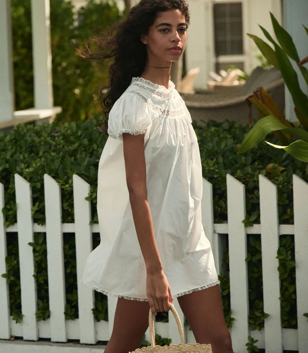 The Daphne Dress by Doen combines refined craftsmanship with effortless style, made from crisp organic cotton poplin for breathability and comfort. Its A-line silhouette and mini-length hem create a light, playful shape, while short puffed sleeves add subtle volume. Detailed with floral scallop lace, delicate pintucks, and a grosgrain ribbon tie at the yoke, this dress is completed with lace trims on the cuffs and hem. Ideal for warm weather occasions, it balances casual ease with elegant detailing.