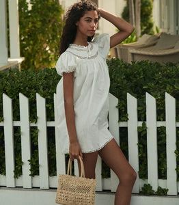 The Daphne Dress by Doen combines refined craftsmanship with effortless style, made from crisp organic cotton poplin for breathability and comfort. Its A-line silhouette and mini-length hem create a light, playful shape, while short puffed sleeves add subtle volume. Detailed with floral scallop lace, delicate pintucks, and a grosgrain ribbon tie at the yoke, this dress is completed with lace trims on the cuffs and hem. Ideal for warm weather occasions, it balances casual ease with elegant detailing.