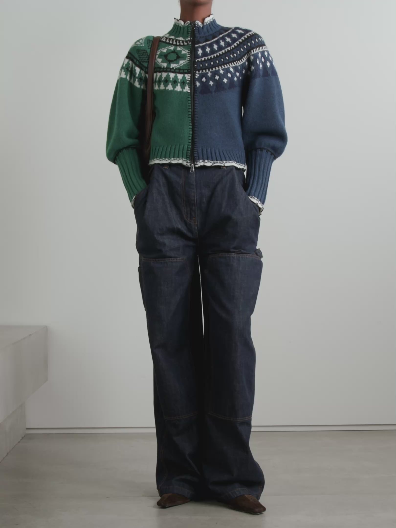 Sea's Linea cardigan masterfully blends two distinct aesthetics into one captivating piece. Crafted from sumptuous merino wool, this intarsia-knit design features Fair Isle-inspired motifs that create visual intrigue, while delicate ruffled trims add an unexpected feminine touch. The clever split construction gives the illusion of contrasting styles sewn together, making it a conversation-starting layer that transforms any basic turtleneck into an effortlessly sophisticated ensemble. 