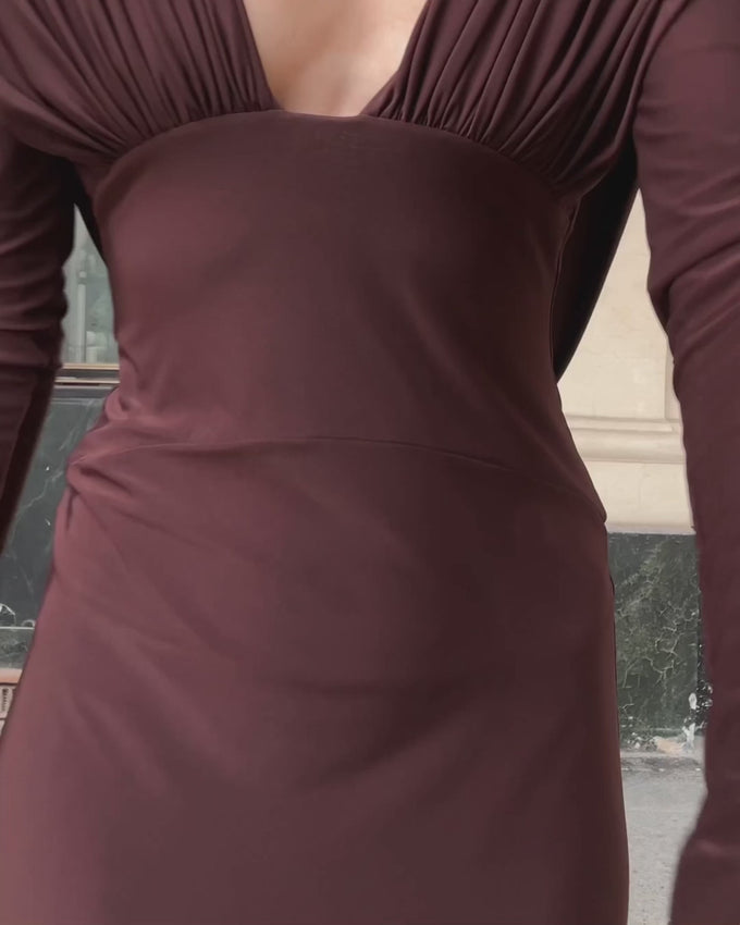 Lucia is a floor-length evening dress in rich cacao that combines elegance with allure. The deep neckline features soft ruching across the bust, while a sculpted waist panel creates a flattering silhouette. Long sleeves provide sophistication, beautifully contrasted by an open back with graceful draping. Perfect for special occasions and evening events, this refined piece balances sensuality with timeless style.
