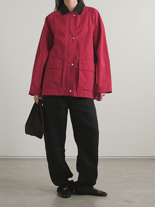 The Elodianna Cotton Jacket by The Row blends classic field-inspired design with modern comfort. Crafted in Italy from durable red cotton canvas, it features a striking black collar and a relaxed fit that you can adjust with waist toggles for a customized silhouette. Practical flap pockets offer easy access to essentials like your phone and keys, making it as functional as it is stylish. Perfect for adding a bold, effortless edge to your wardrobe.