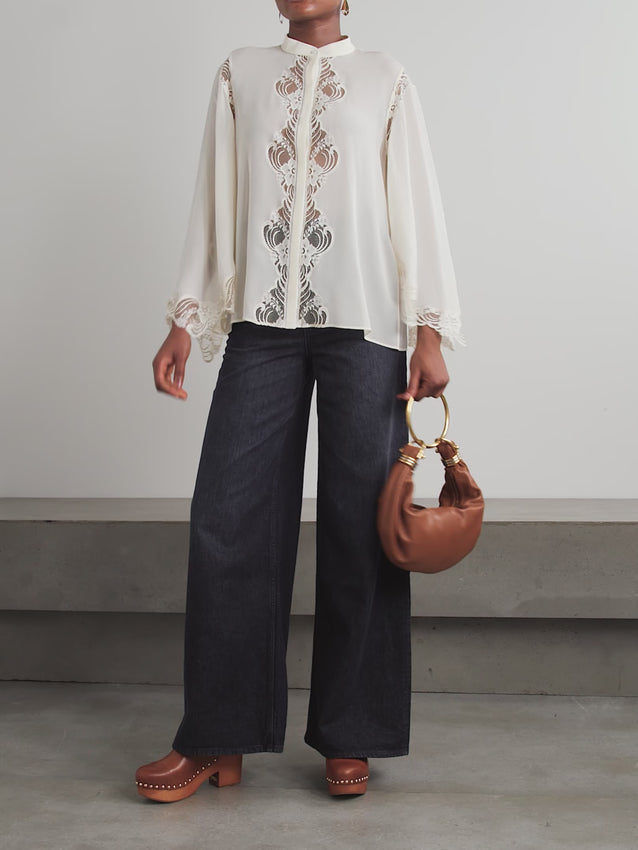 A bohemian-inspired blouse celebrating artisanal craftsmanship. Constructed from lightweight organic silk-georgette with graceful bell sleeves, it features intricate lace trim and hand-detailed ladder embroidery along the placket and back yoke. Pair with a suede jacket to enhance the rich textural interplay.