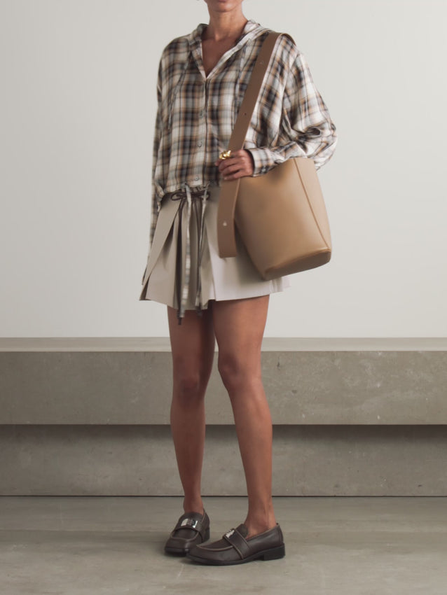 Crafted from a luxurious cotton and silk-blend fabric, this mini skirt features refined leather trim detailing that elevates its layered silhouette. The combination of natural fibers offers breathable comfort while maintaining an elegant drape, making it perfect for both casual and polished occasions. The leather accents add a contemporary edge to the timeless layered design.