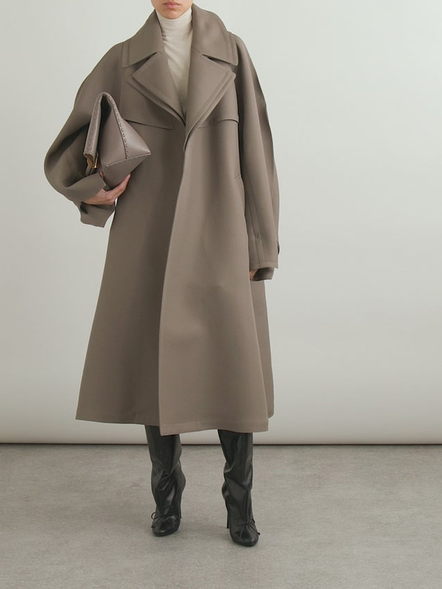 Pieter Mulier reimagines the timeless trench for Alaïa's Fall '24 collection with bold, unexpected twists. This oversized wool-blend twill coat layers texture and silhouette in the most delightful way—think doubled lapels that make a statement and cutout sleeves finished with clever tab details at the cuffs. It's heritage craftsmanship with a playful wink, perfect for those ready to elevate their outerwear game with something truly distinctive.