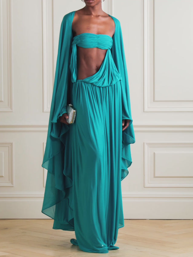 Experience the elegance of Christopher Esber’s Gyre dress, a stunning blend of volume and fluidity. Crafted from soft jersey, this maxi dress features a graceful cape-effect overlay and a bandeau bodice that cascades to a floor-length hem, creating effortless movement. Its vibrant turquoise hue draws attention, while the design’s delicate draping highlights your silhouette. Perfectly paired with silver jewelry, this statement piece embodies refined sophistication for any special occasion.