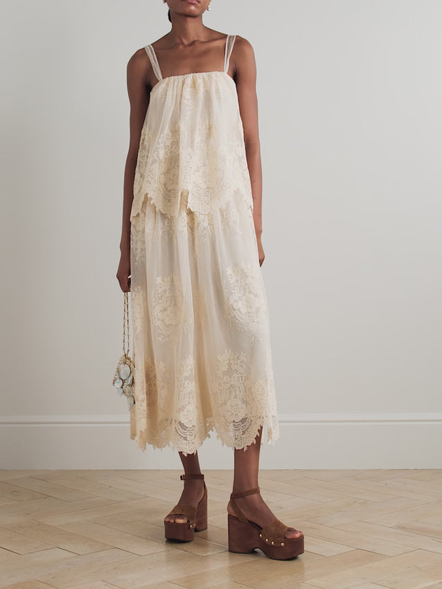 Experience the elegance of Zimmermann's Tiered Lace Midi Dress, featuring straps delicately embroidered with poetic detail. Crafted from soft lace that cascades in graceful tiers, its vintage-inspired silhouette evokes timeless charm. The creamy hue pairs beautifully with gold-tone jewelry, creating a refined and sophisticated look perfect for special occasions. Embrace effortless style and timeless femininity with this exquisite dress.
