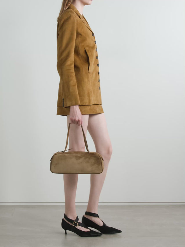 The Saraphina Jacket by Khaite embodies effortless sophistication with its relaxed yet structured silhouette. Crafted from luxurious tan suede, this piece features padded shoulders that create a refined shape while maintaining an easy, unstructured feel. Vertical welt pockets offer practical elegance, while a row of horn buttons adds timeless detail. The full satin-twill lining ensures comfort and durability with every wear. A versatile layer that transitions seamlessly from day to evening.