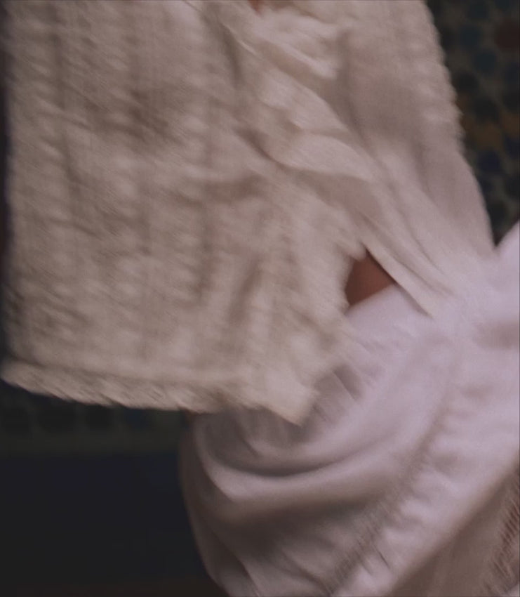 Crafted from luxurious organic cotton voile, the Bernadette Top showcases an eye-catching ruffle adorning the collar and center front, layered with sheer tulle and three distinctive lace patterns. The gently cropped bodice is enhanced with pintucks and delicate lacework, while mother-of-pearl buttons trace a graceful line down the front. Refined lace edging frames the collar and sleeve cuffs for an elegant finish.