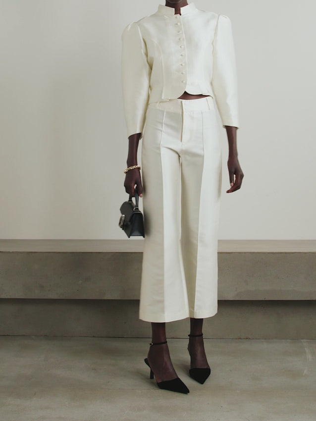 A striking reimagining of 1950s tailoring with unmistakably modern flair. The Amoako Cropped Faille Jacket in Ivory celebrates Parisian design through bold architectural lines and sculptural silhouettes. Mandarin collar, dramatic puff sleeves, and a sharply cinched waist create visual impact, while the cropped cut delivers contemporary proportion. Pure elegance with structural attitude.