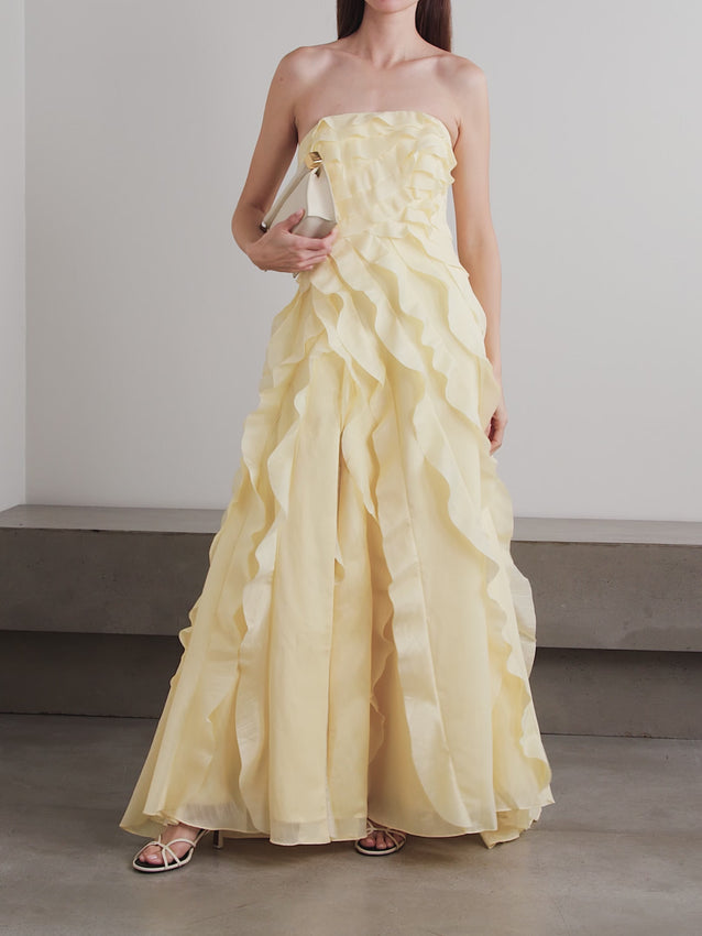 Elegant strapless gown crafted from luxurious faille fabric. Features delicate ruffled detailing and shirred construction throughout for a refined silhouette. The strapless neckline offers a sophisticated, timeless look perfect for formal occasions. Flattering shirring creates dimension and movement while the structured faille maintains its shape beautifully. An ideal choice for evening events, galas, or special celebrations where understated glamour is desired.