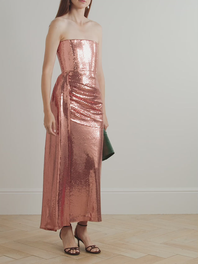 Breathtaking in every light, this asymmetric draped sequined mesh dress features a strapless boned bodice that sculpts an elegant silhouette. Shimmering sequined mesh catches the eye while a graceful draped overlay flows down the skirt, creating movement and dimension. The structured bodice pairs beautifully with the fluid draping for a statuesque, show-stopping look perfect for special occasions.