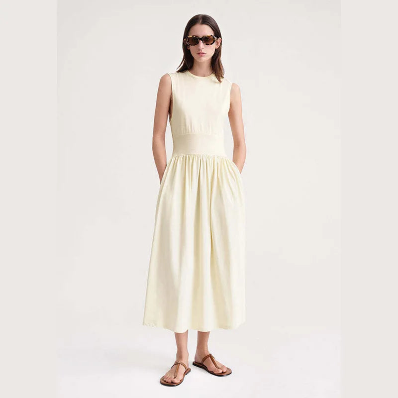 Indulge in luxury with our Robe Yolanda. This minimalist dress for women features a waist-slimming A-line silhouette and a flared midi skirt, accentuated by a vanilla white cotton fabric. The classic round neckline and sleeveless design add a touch of sophistication to this must-have summer piece.