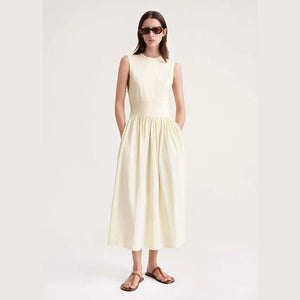 Indulge in luxury with our Robe Yolanda. This minimalist dress for women features a waist-slimming A-line silhouette and a flared midi skirt, accentuated by a vanilla white cotton fabric. The classic round neckline and sleeveless design add a touch of sophistication to this must-have summer piece.